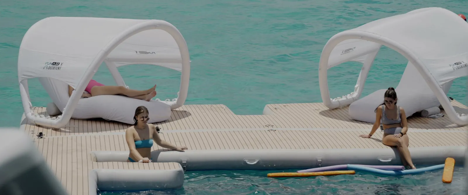 Guests relaxing under shaded cabanas on the floating beach club
